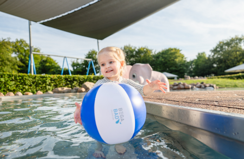 Kleines Mädchen im Kinderbecken mit Wasserball