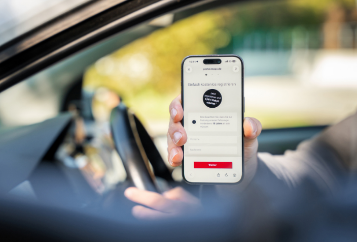 Hand zeigt ein Smartphone mit der MOQO-App.