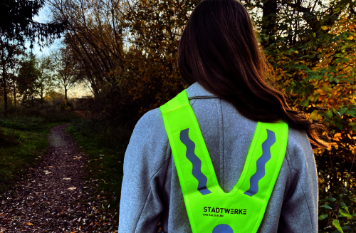 Mädchen mit Warnweste geht einen Weg entlang