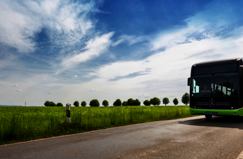 Bus fährt auf der Straße an einem Feld entlang