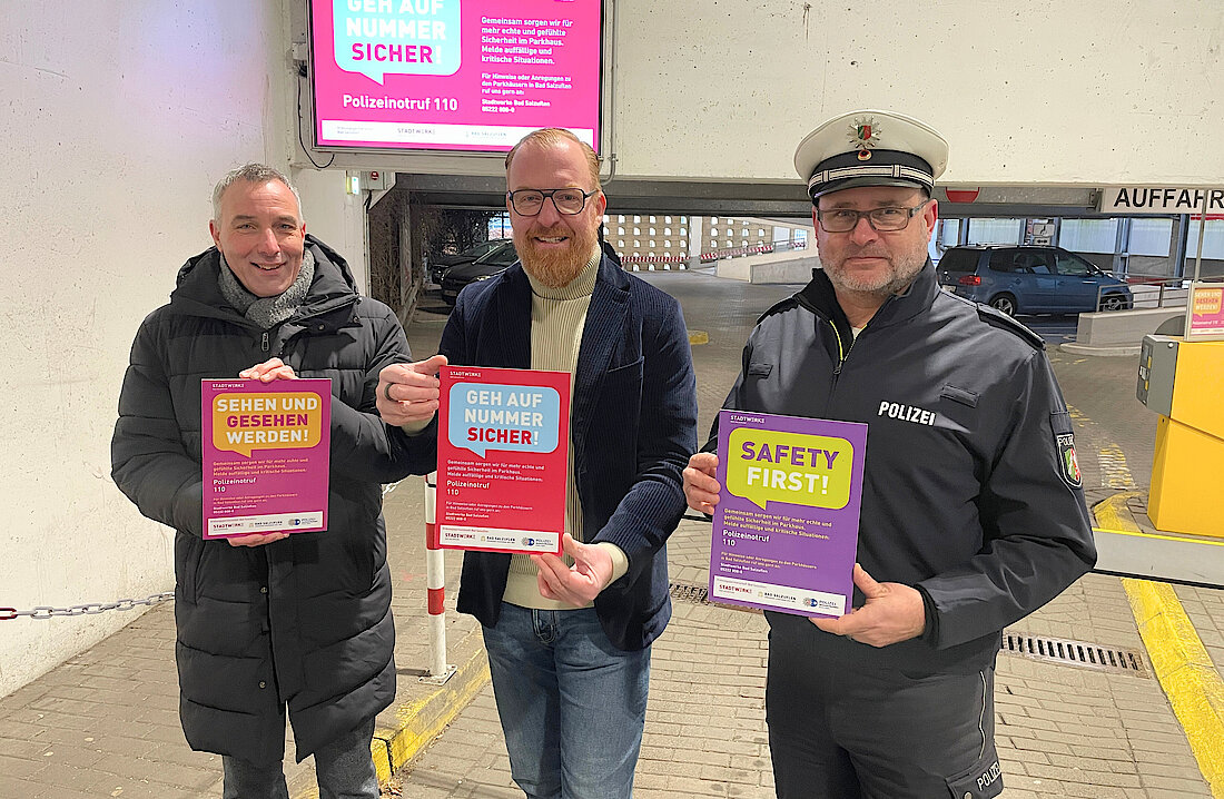 Bürgermeister Dirk Tolkemitt, Stadtwerke Geschäftsführer Volker Stammer und erster Polizeihauptkommissar Marc Krumsiek präsentieren die neue Sicherheitskampagne im Parkhaus Zentrum.
