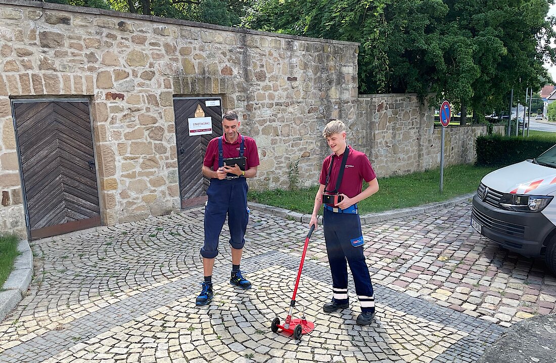 Zwei Kollegen überprüfen Erdgasleitungen auf dem Parkplatz des Schötmaraner Schlosses 